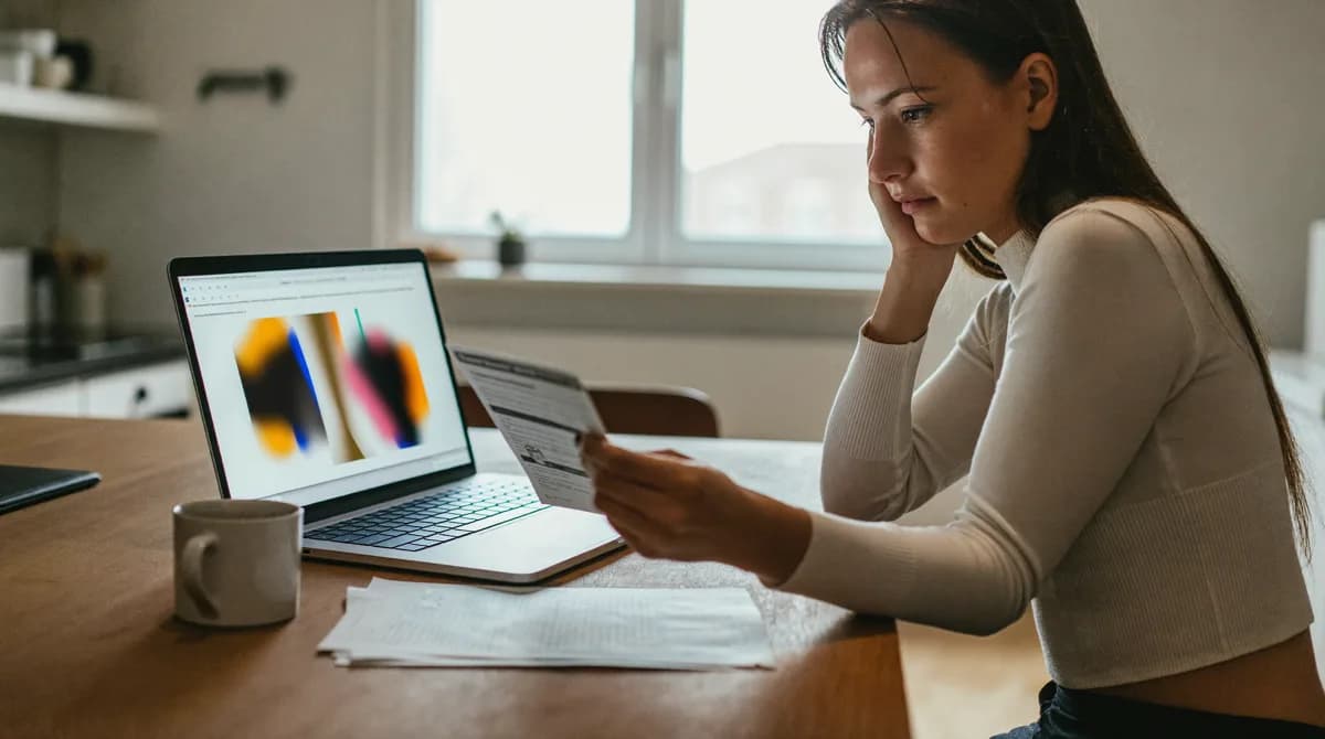 Frau prüft am Küchentisch Stromtarife auf dem Laptop